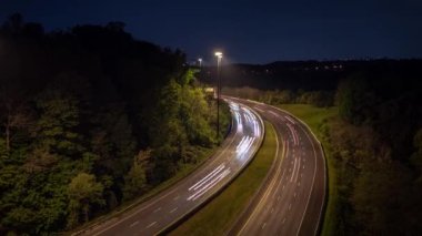 Gece Toronto şehir merkezine giden kıvrımlı bir otoyol üzerindeki trafik ışıkları ve stop lambaları, yolun kenarlarında ağaçların oluşturduğu uzun süreli ışıklara maruz kalıyor..