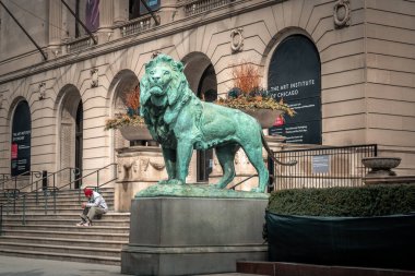Chicago, IL - 24 Mart 2020: Chicago şehir merkezindeki Sanat Enstitüsü 'nün merdivenlerinde oturan bir adam, COVID-19 ya da Coronavirus salgınının ortasında ürkütücü derecede sessiz bir günde aslanların girişini süslüyor..
