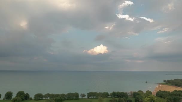 青い空を満たすふわふわの白い雲の空中のタイムラプスそして日没の間にシカゴとフォスタービーチの北側のミシガン湖の上で消える — ストック動画