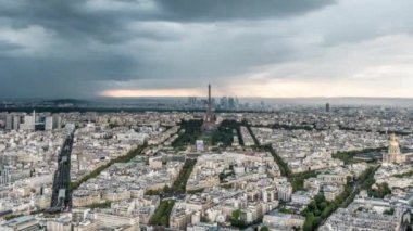 Paris 'te Eyfel Kulesi üzerinde fırtına bulutları ve yağmur bulutlarının havada uçuşması caddelerde ve caddelerde trafik oluşurken ve inşaat vinçleri binalarda çalışırken.