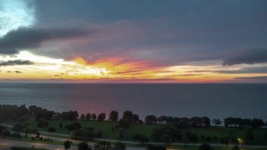 Gökyüzü pembe, turuncu ve sarı renkli bulutlarla dolup taşarken ve trafik Chicago 'nun Edgewater Mahallesi' ndeki Lake Shore Drive 'da sabah erken saatlerde hızlanmaya başlarken hava gündoğumu zamanı da artmaya devam ediyor..