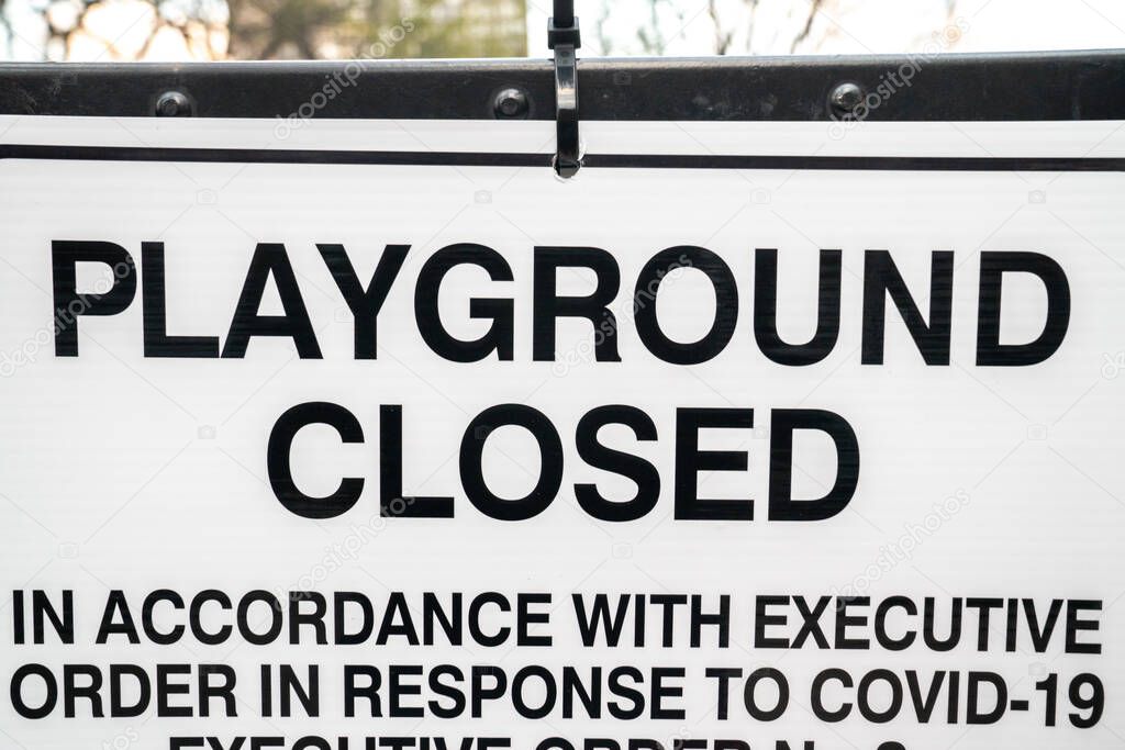 A black and white sign hangs on the fence at a playground in Chicago due to the executive orders by the local government to close down during the COVID-19 pandemic and stay at home orders.