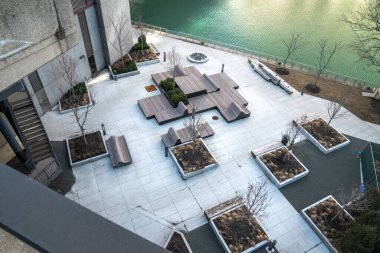 Chicago, IL - 10 Mart 2020: Güzel dizayn edilmiş ahşap banklar ve yükseltilmiş beton ekme yatakları olan plaza Chicago Nehri kıyısında ilkbaharın başlarında boş oturuyor..