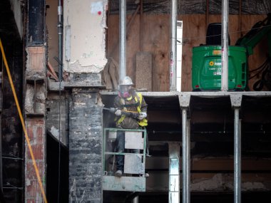Chicago, IL - 10 Mart 2020: Bir inşaat işçisi, tarihi Tribune Kulesi 'nin yenilenmesi ve konutlara dönüştürülmesi sırasında eski bir taş ustasını çelik kuleden ayırmak için bir matkap kullanıyor.