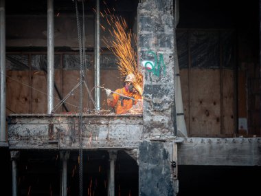 Chicago, IL - March 10th, 2020: An iron worker uses torches and tools to cut through an existing beam being removed during the renovation and conversion of a portion of the Tribune Tower. clipart
