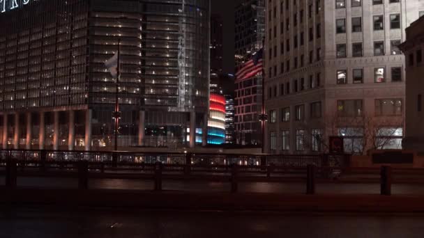 シカゴ 2020年4月22日 トランプ国際ホテルとタワーの駐車場の入り口がCovid 19パンデミックの間に赤白と青で点灯すると 風の中のアメリカとシカゴの旗のフラップ — ストック動画