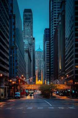 Chicago, IL - 22 Nisan 2020: Şikago Ticaret Kurulu çok sessiz bir Lasalle Caddesi 'nin sonunda COVID-19 salgını sırasında kasvetli ve rutubetli bir akşamda oturur ve ev siparişlerinde kalır..