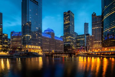 Chicago, IL - 22 Nisan 2020: Merchandise Mart, COVID-19 salgını sırasında Salesforce Kulesi 'nin inşaat malzemelerinin boş durduğu nemli bir akşamda mavi ışıkta parlıyor.
