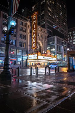 Chicago, IL - 22 Nisan 2020: Bir polis minibüsü kapalı Chicago Tiyatrosu 'nun önündeki boş caddede oturur ve COVID-19 salgını sırasında her gece aydınlanır ve ev siparişlerinde kalır..