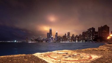 Chicago 'nun ufuk çizgisi zaman çizelgesinde güzel bir dönüş. Beyazlar aşınmış beton kaldırım üzerinde dalış işareti yok ve bina ve şehir ışıklarından aydınlanan ağır bulut örtüsü..