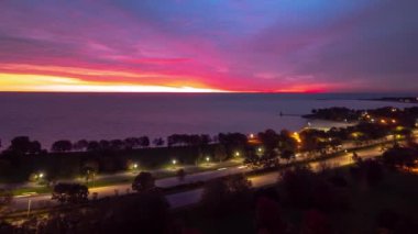 Gökyüzü pembe, sarı, mavi, mor, turuncu ve kırmızı renkte bulutlara doğru hızla ilerlerken Chicago 'da Lake Shore Drive' da trafik birikiyor..