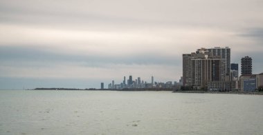 Chicago şehrinin panoramik manzarası kuzey tarafındaki Loyola parkından Michigan Gölü 'nün suyu ve baharda yukarıdaki bulutlu gri gökyüzü ile gökyüzü..