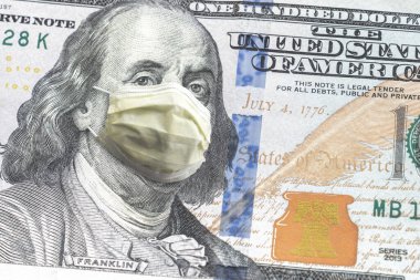 ABD kağıt para birimini kapatın. 100 dolarlık banknot. Benjamin Franklin, COVID-19 salgınından dolayı sarı doktor maskesi takıyor..
