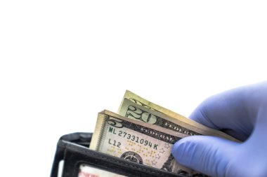Siyah deri bir cüzdanda bulunan ve beyaz arka planda izole edilmiş mavi lateks eldiven takan beş ve yirmi dolarlık banknotlar da dahil olmak üzere nakit çeken kişiye yaklaş..