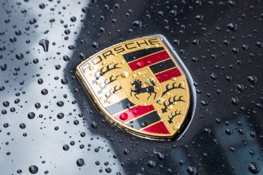 Porsche Logo Close Up on a black car with rain drops. clipart