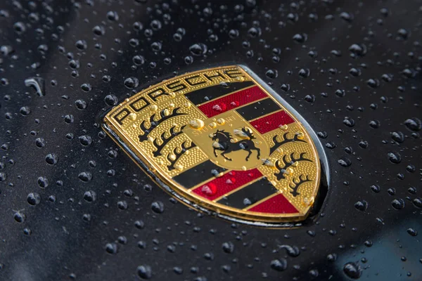 Porsche logo bliska na czarnym samochodzie z kropli deszczu. — Zdjęcie stockowe