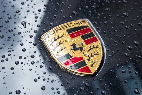 Porsche logo Close up na černém autě s dešťové kapky. — Stock fotografie