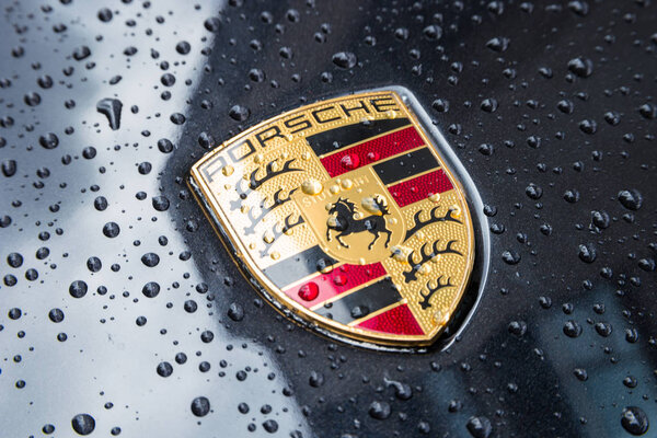 Porsche Logo Close Up on a black car with rain drops.