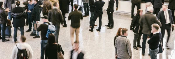 Crowd of anonymous people walking in trade show a hall