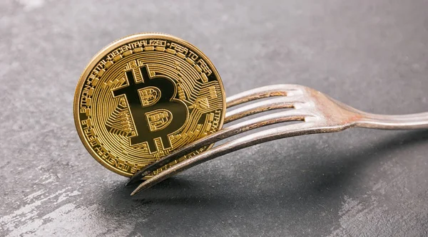 Golden Bitcoin (btc) in einer Gabel auf dunklem Hintergrund, Konzeptbild für eine Bitcoin-Gabel. ideal für Webseiten und Zeitschriftenlayouts — Stockbild Bitcoin (btc) harte Gabel, goldene Kryptowährung Konzept Bild — Stockfoto