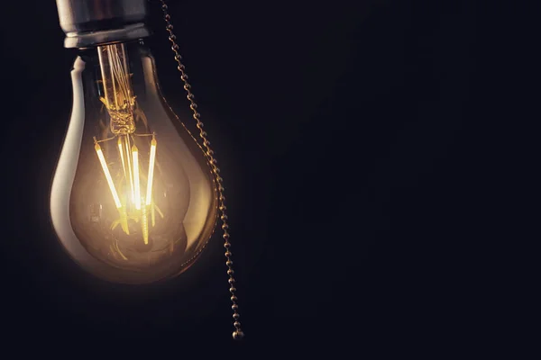 Vintage pendurado lâmpada com interruptor sobre fundo escuro — Fotografia de Stock