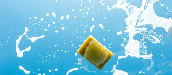 Sponge with soap on a glass window — Stock Photo, Image