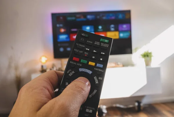 Mano masculina que sostiene el control remoto de la TV, disparo del punto de vista —  Fotos de Stock