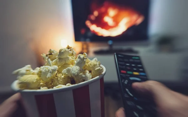 Young man watching a movie with popcorn and remote controller, P — Stock Photo, Image