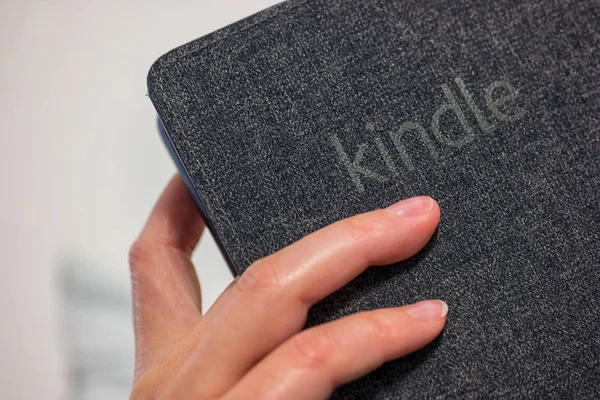 Kvinna hand innehav virker-bok läsaren (Amazon Kindle Paperwhite) i handen — Stockfoto