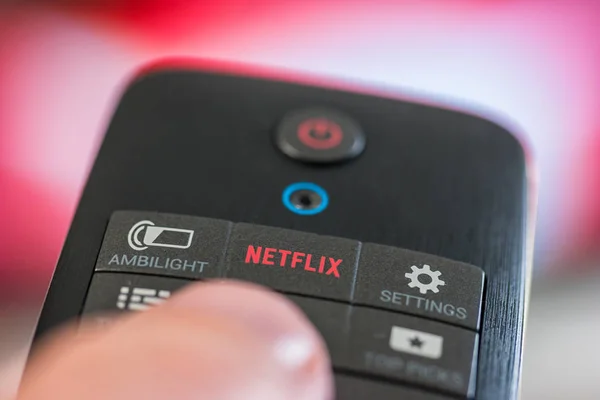 Adam bir Netflix düğme uzaktan kumandayla tutar — Stok fotoğraf