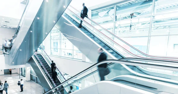 Gente de negocios borrosa en una escalera mecánica — Foto de Stock