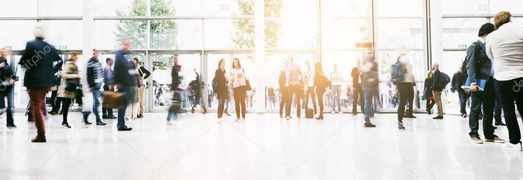 large crowd of anonymous blurred people at a trade show hall