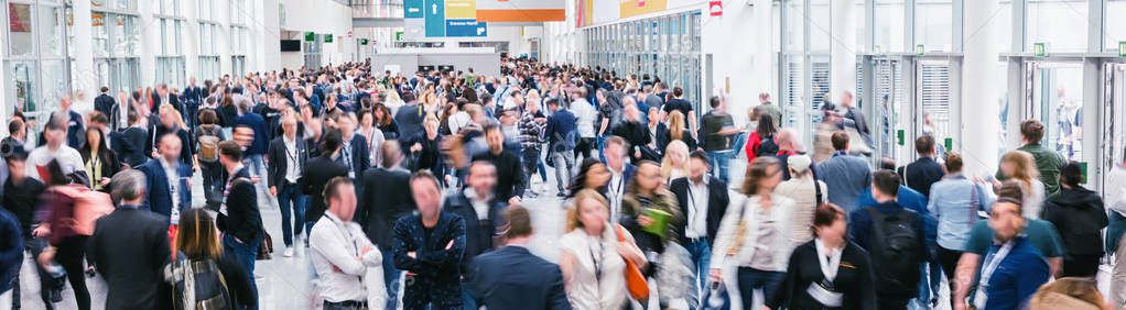 large crowd of anonymous blurred people at a trade show