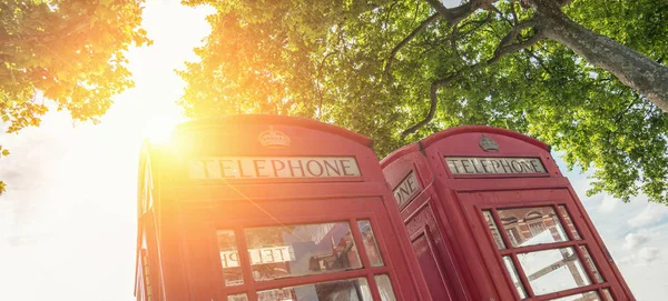 view of a red phone booths in the street of london with sunshine light. ideal for websites and magazines layouts
