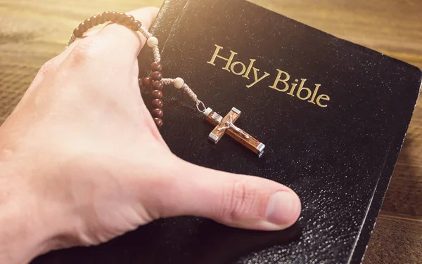 Ręka trzyma Świętą Biblię z krucyfiksem — Zdjęcie stockowe