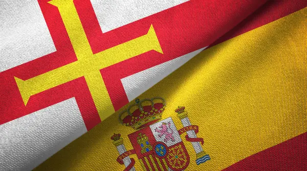 Guernesey et Espagne deux drapeaux tissu textile, texture du tissu — Photo