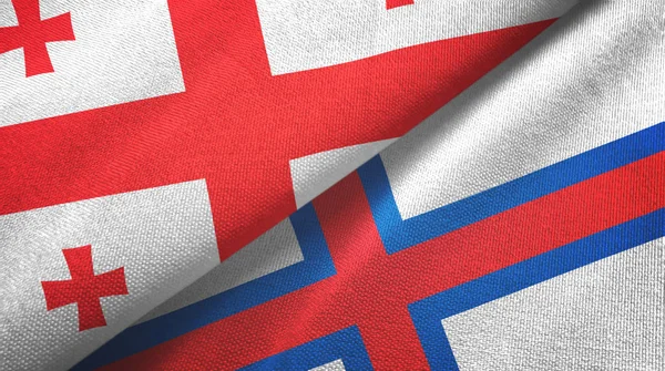 Gruzja i Wyspy Owcze dwie flagi tkaniny tekstylne, tekstura tkaniny — Zdjęcie stockowe