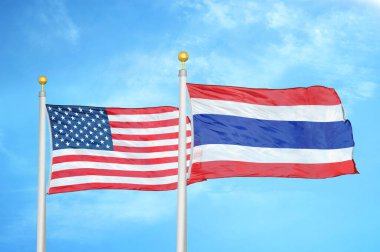 ABD ve Tayland bayrak direkleri ve mavi bulutlu arka planda iki bayrak