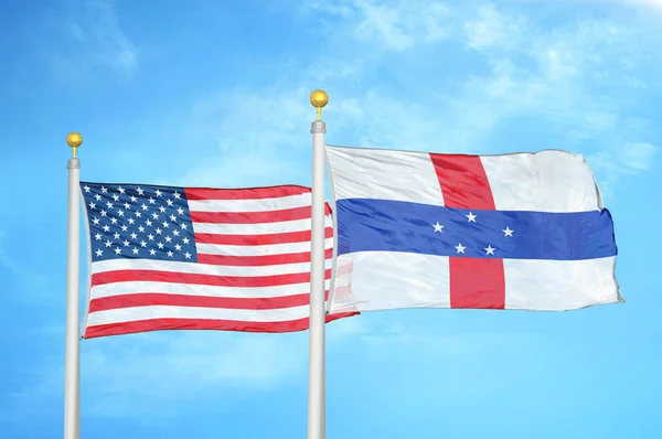 United States and Netherlands Antilles two flags on flagpoles and blue cloudy sky background