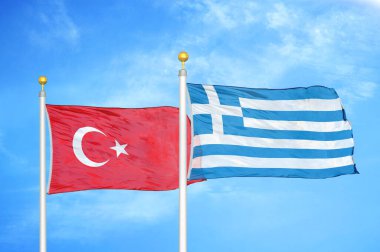 Türkiye ve Yunanistan bayrak direkleri ve mavi bulutlu arka planda iki bayrak