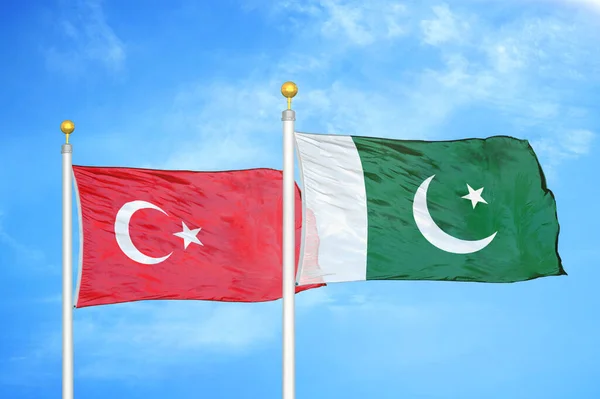 Turkey and Pakistan two flags on flagpoles and blue cloudy sky background