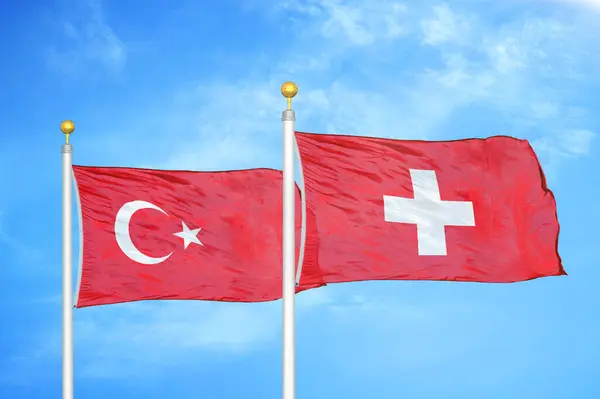 トルコとスイスの旗竿と青空の背景に2つの旗 — ストック写真