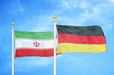 İran ve Almanya bayrak direkleri ve mavi bulutlu arka planda iki bayrak