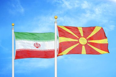 İran ve Kuzey Makedonya bayrak direkleri ve mavi bulutlu arka planda iki bayrak