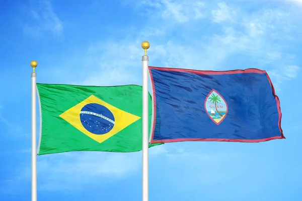 巴西和关岛旗杆上的两面旗帜和蓝云的天空背景 — 图库照片