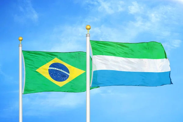 巴西和塞拉利昂旗杆上的两面旗帜和蓝天背景 — 图库照片