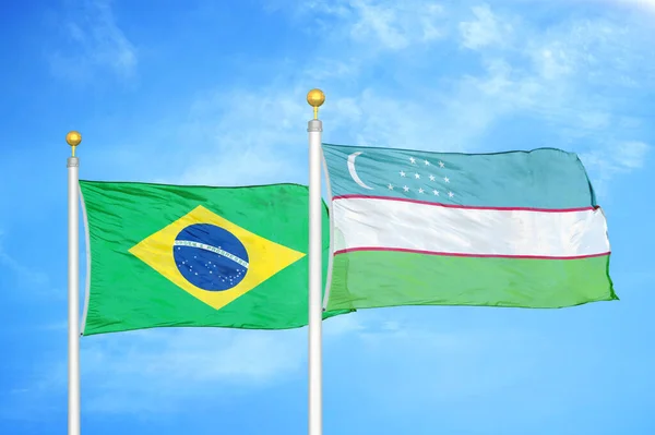 巴西和乌兹别克斯坦两面旗杆上的国旗和蓝色阴天背景 — 图库照片