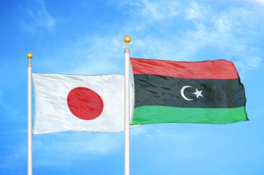 Japonya ve Libya bayrak direkleri ve mavi bulutlu arka planda iki bayrak