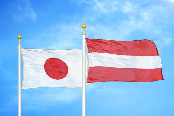 日本とオーストリアの旗竿と青空の背景に2つの旗 — ストック写真