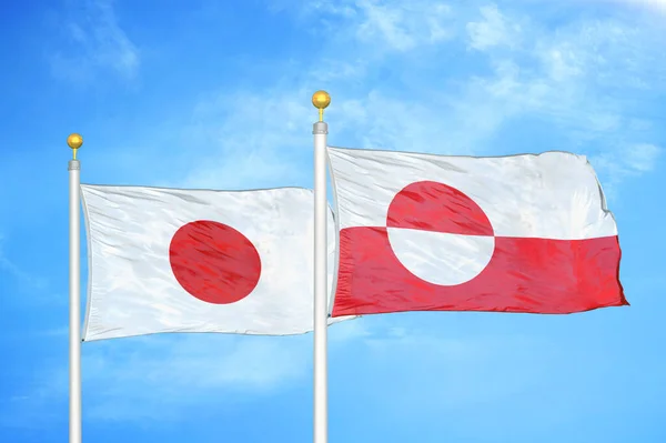 旗竿に日本とグリーンランドの二つの旗と青い空の背景 — ストック写真
